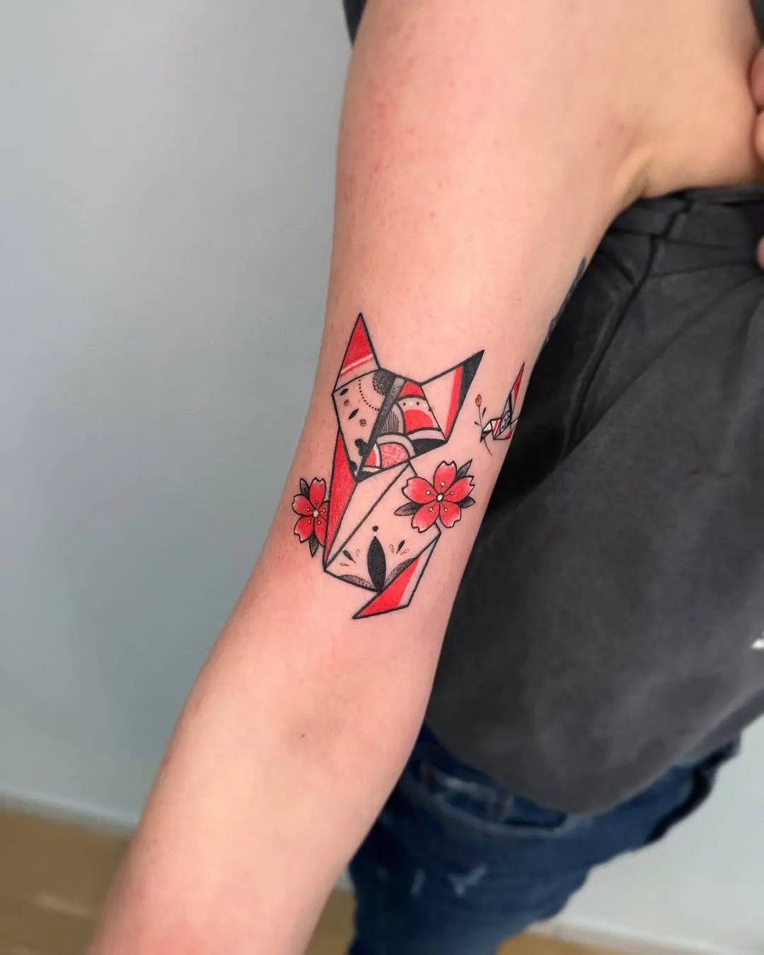 Vibrant origami fox tattoo with floral accents