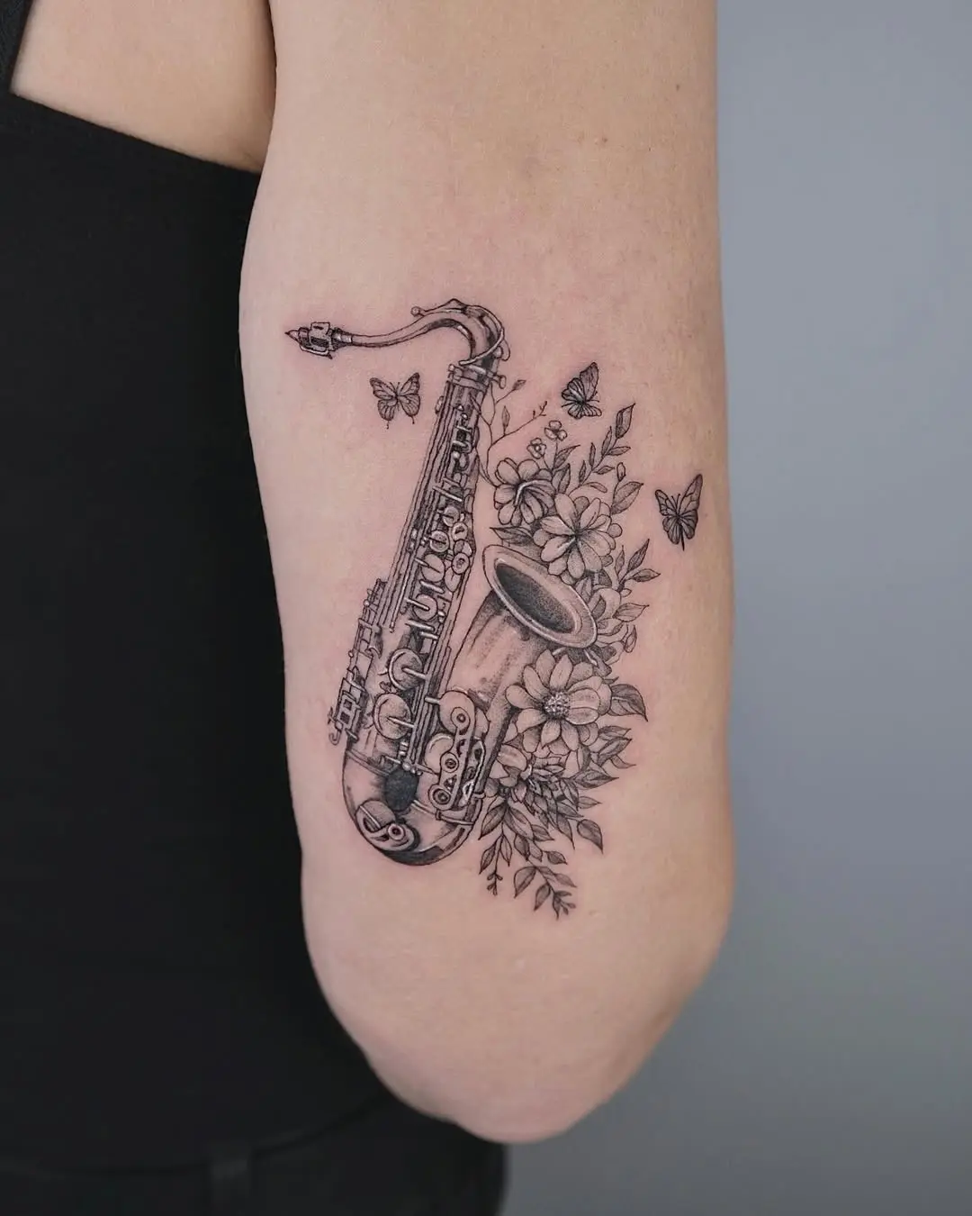 Artistic saxophone tattoo surrounded by flowers