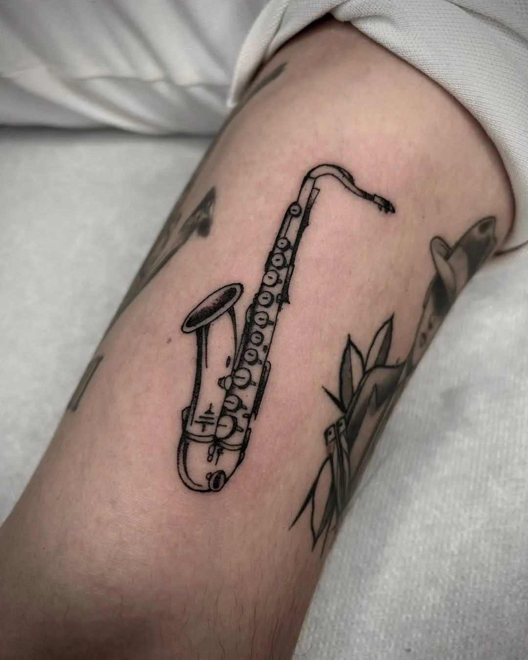 Minimalist saxophone tattoo showcasing musical passion