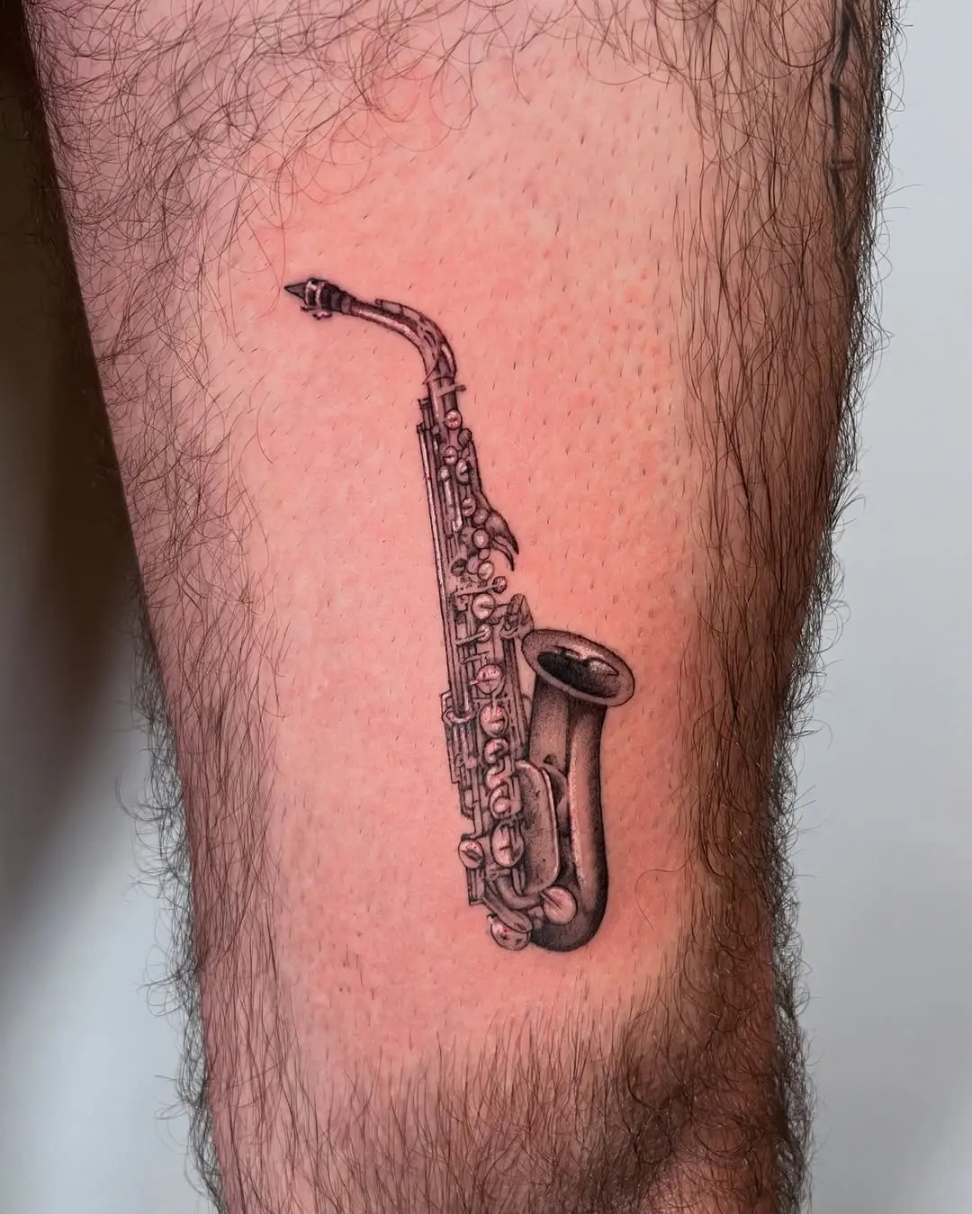 Intricate saxophone tattoo on the leg