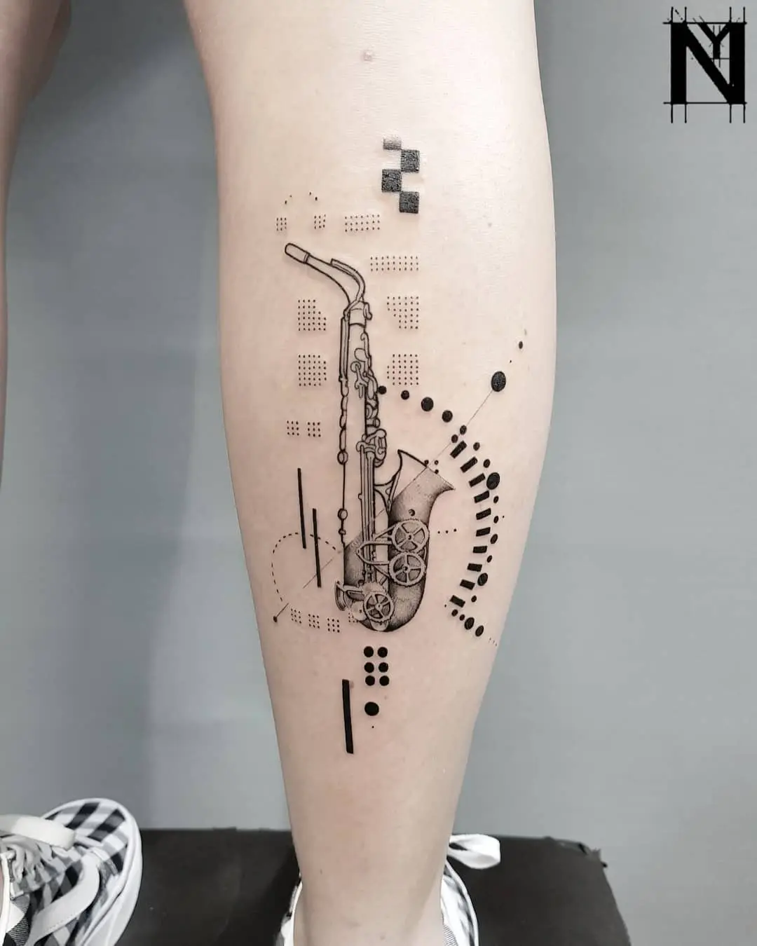 Minimalist saxophone tattoo with abstract elements
