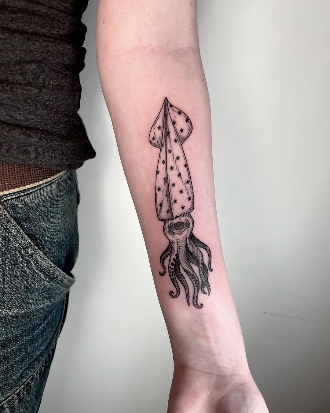Starlit squid tattoo on forearm