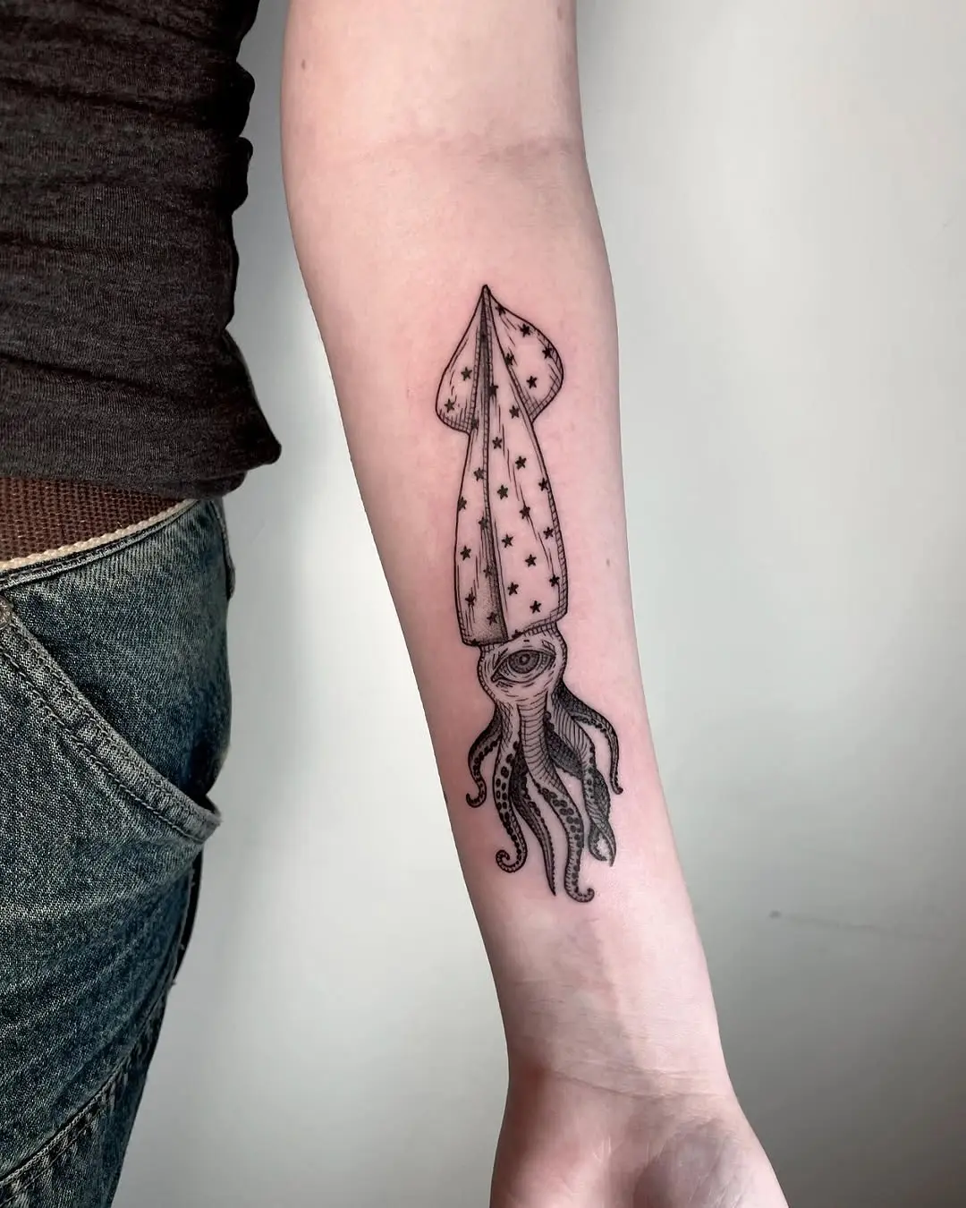 Starlit squid tattoo on forearm