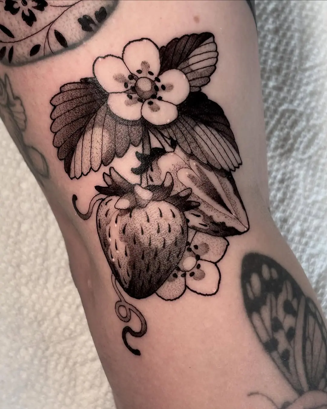 Elegant strawberry tattoo with floral details