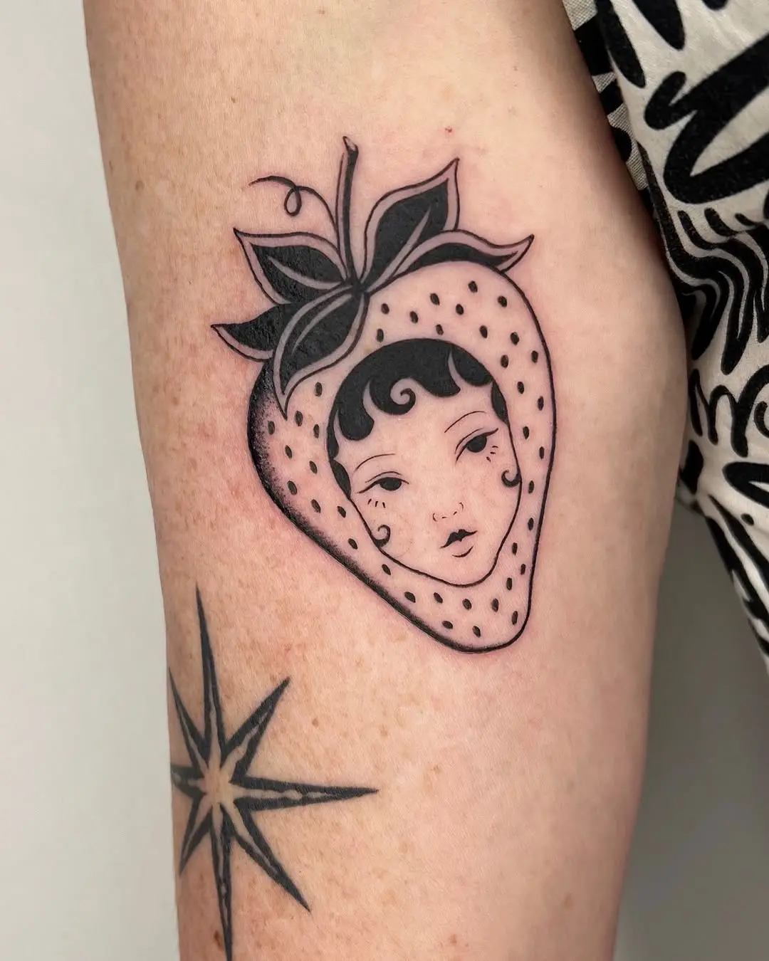 Creative Strawberry Tattoo Featuring a Unique Face