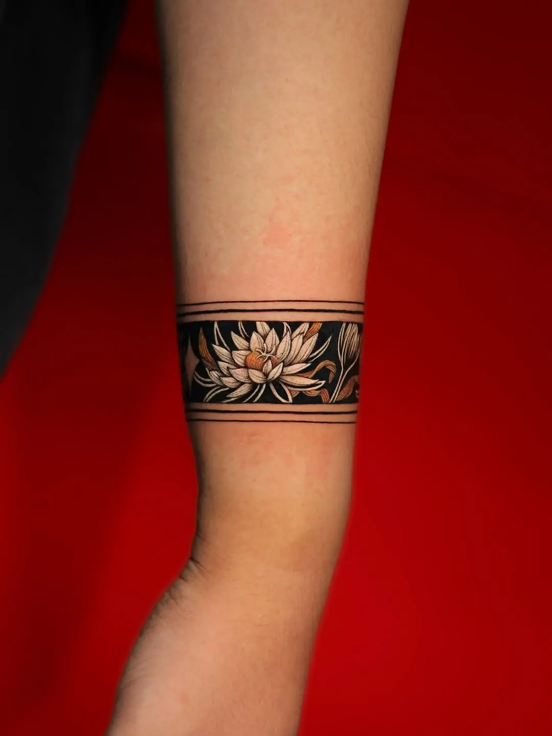 Elegant armband tattoo featuring delicate lotus flowers