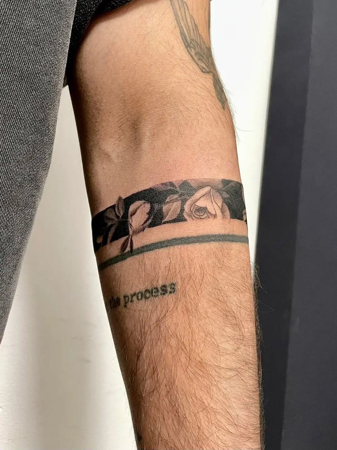 Unique armband tattoo featuring roses and text