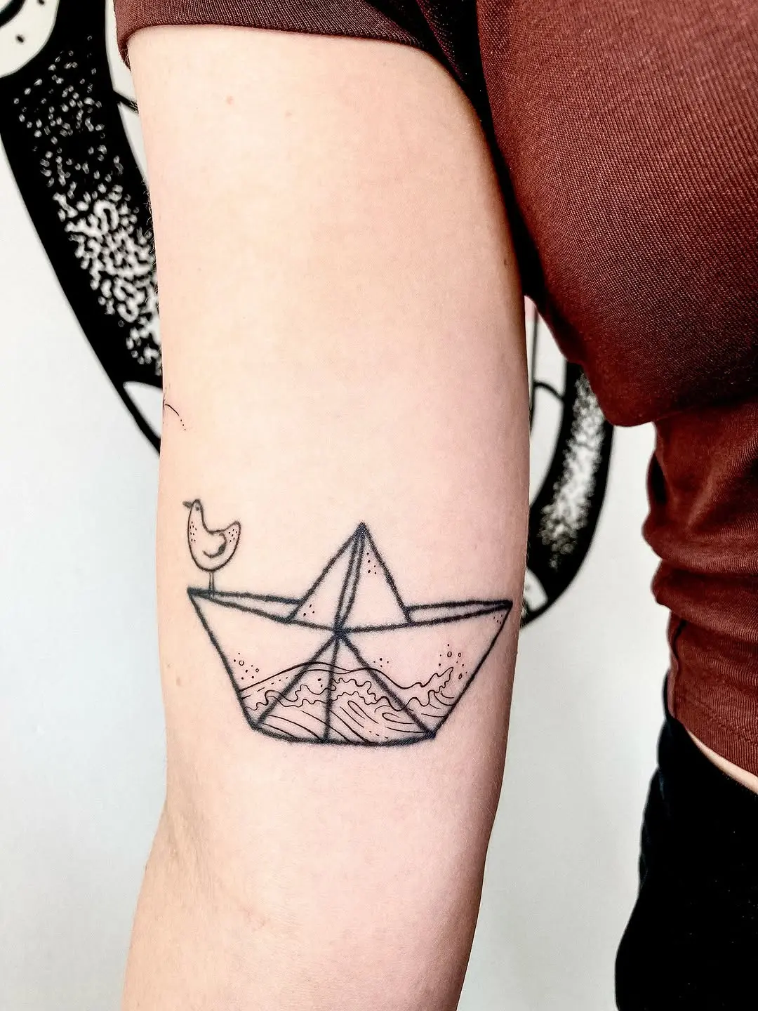 Minimalist boat tattoo with waves and bird