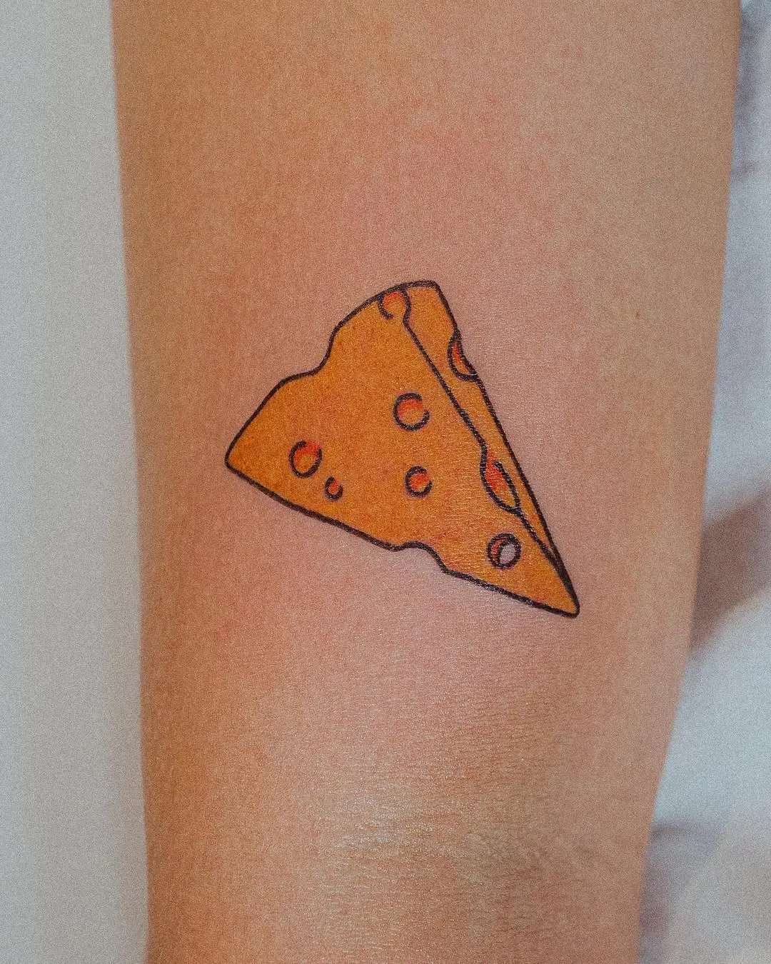 Unique cheese slice tattoo on arm