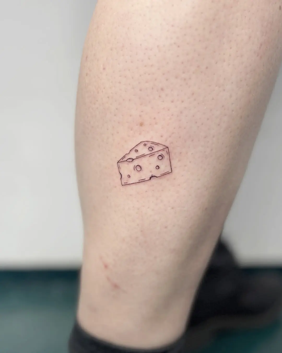 Cute cheese tattoo on calf showcases simplicity.