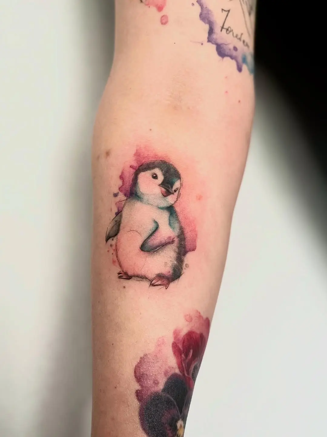 Charming watercolor penguin tattoo on the arm