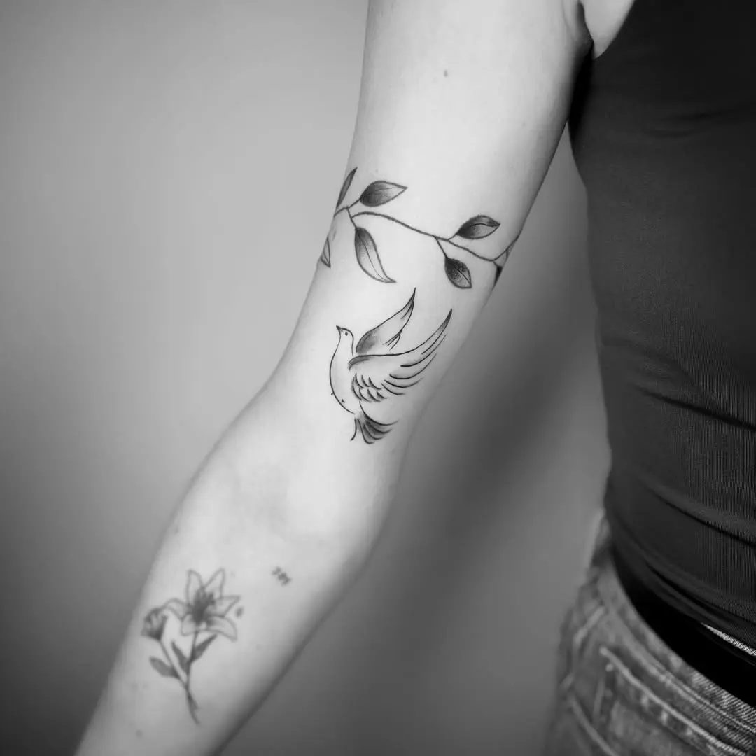 Elegant dove tattoo surrounded by flowing leaves