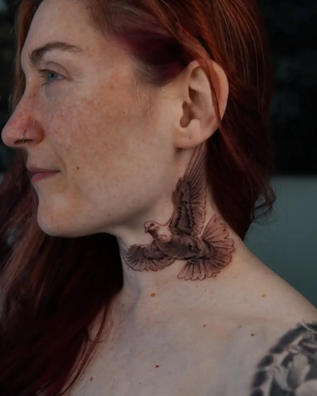 Elegant dove tattoo soaring on the neck.