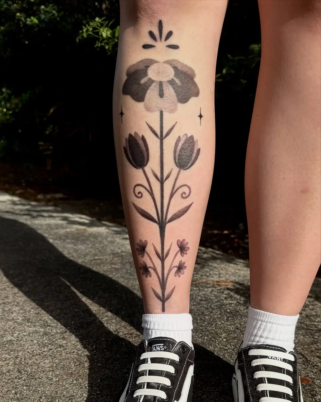 Stylish floral shin tattoo in black and grey
