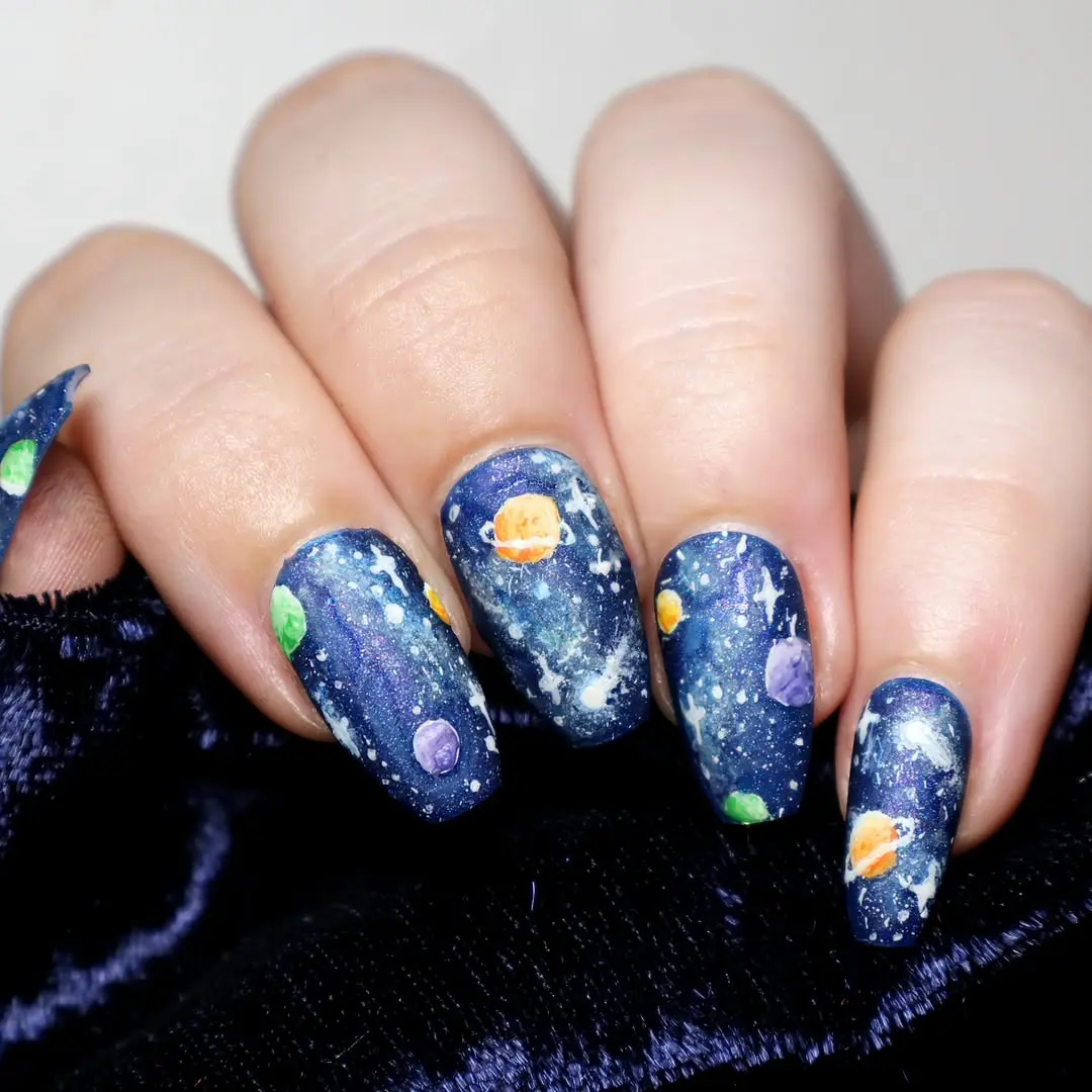 Celestial-themed galaxy nails with colorful planets