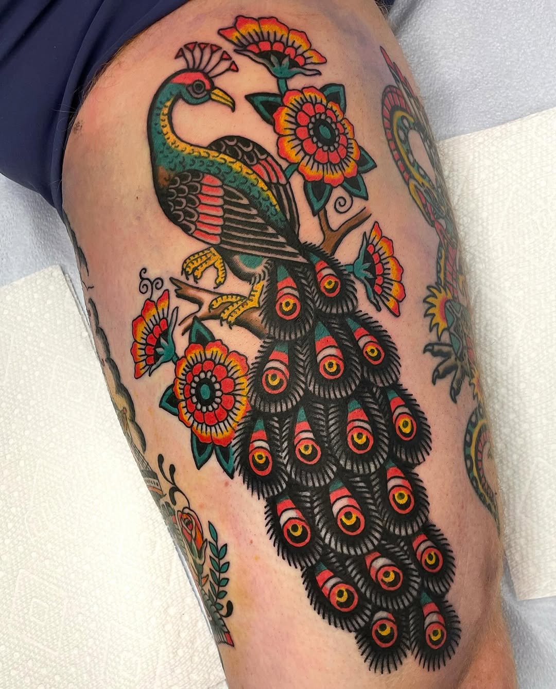 Stunning peacock tattoo with vibrant floral accents