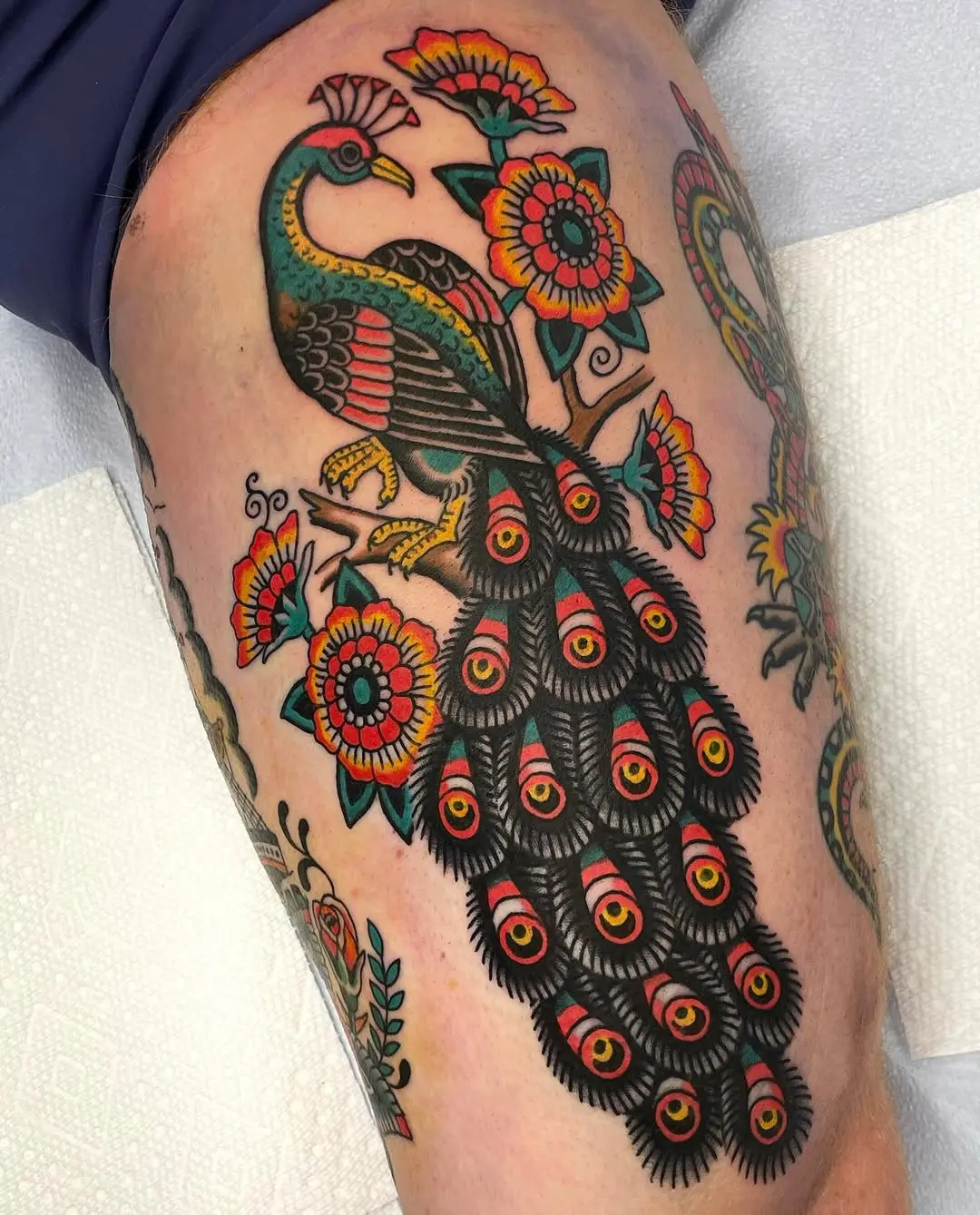 Stunning peacock tattoo with vibrant floral accents