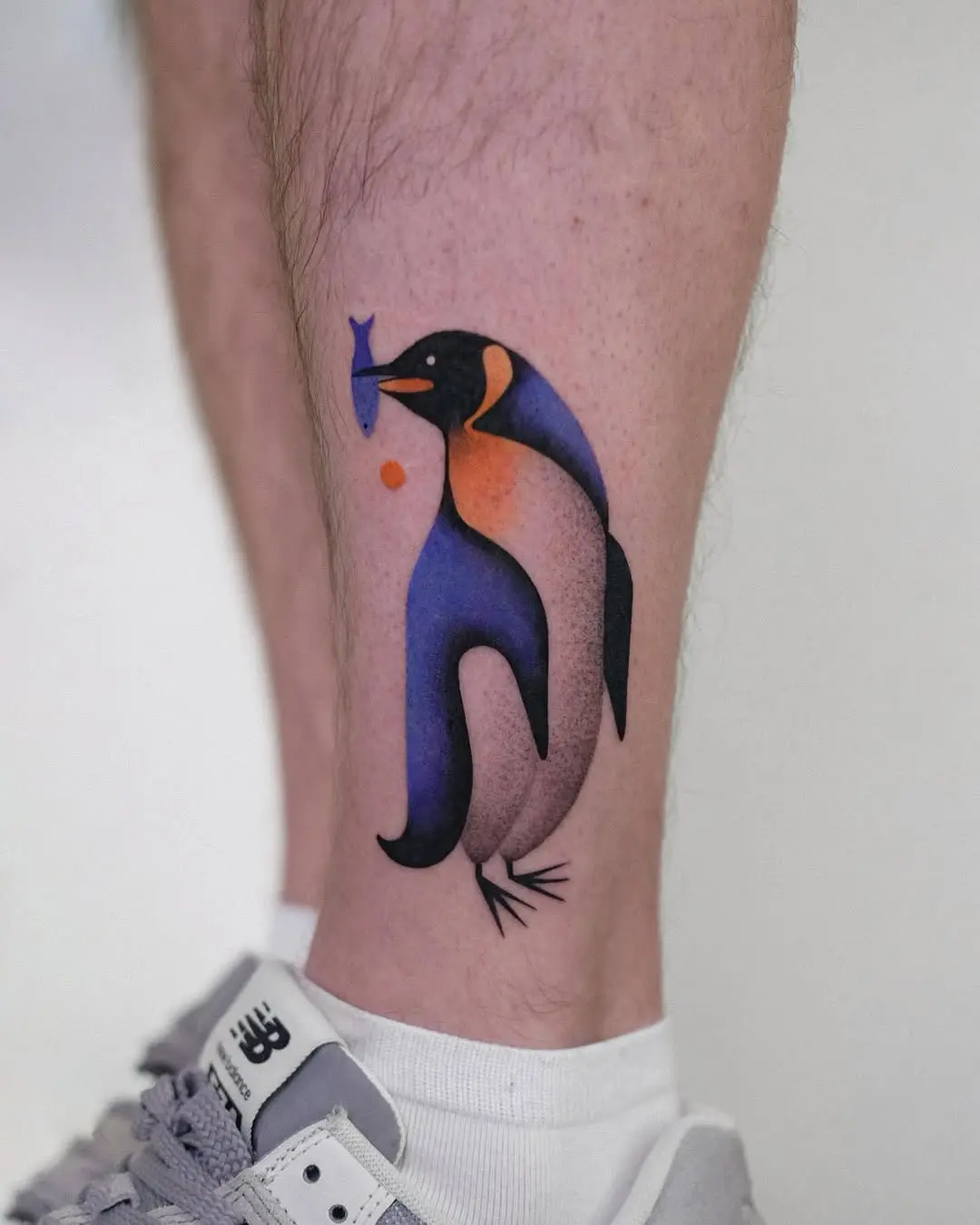 Vibrant artistic penguin tattoo with fish