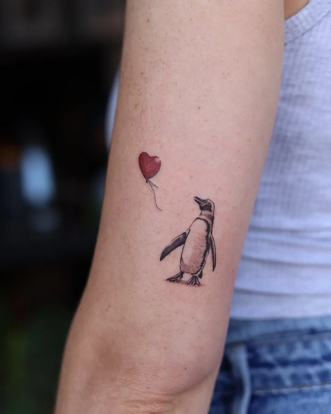 Charming penguin tattoo with a whimsical balloon