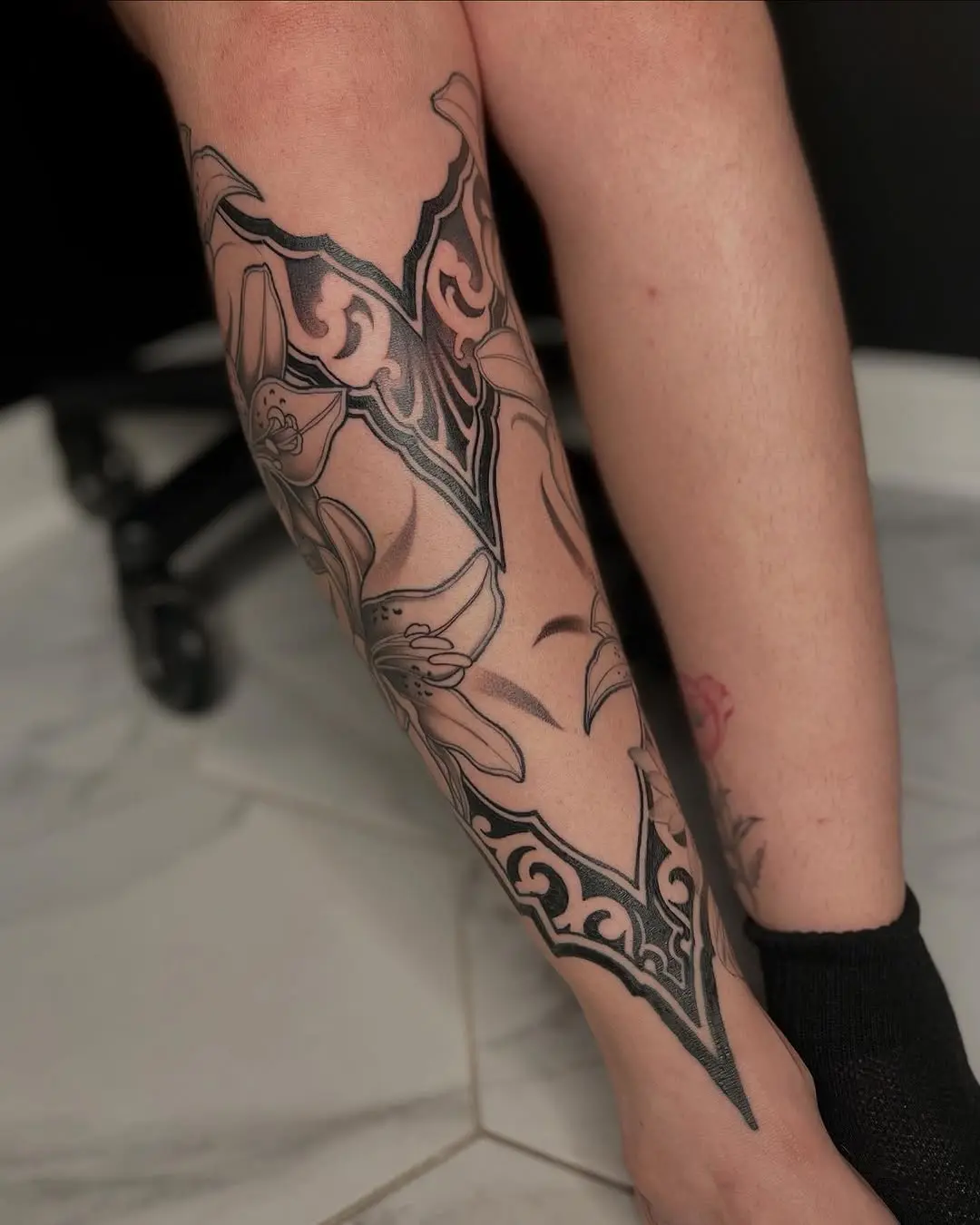 Elegant black and grey floral shin tattoo design
