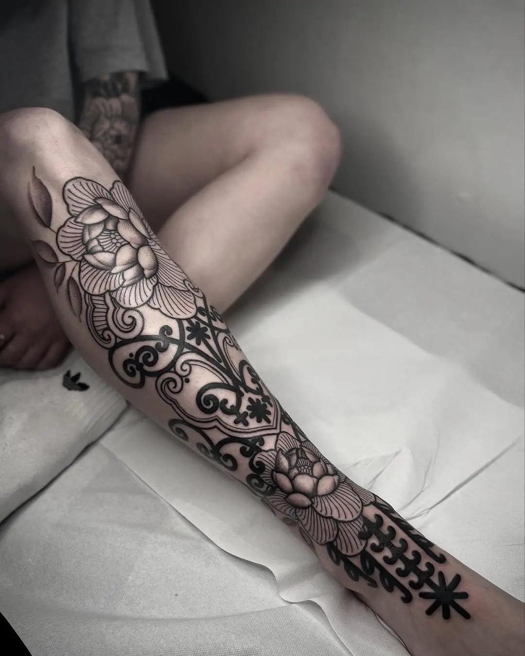 Elegant floral shin tattoo design in black ink