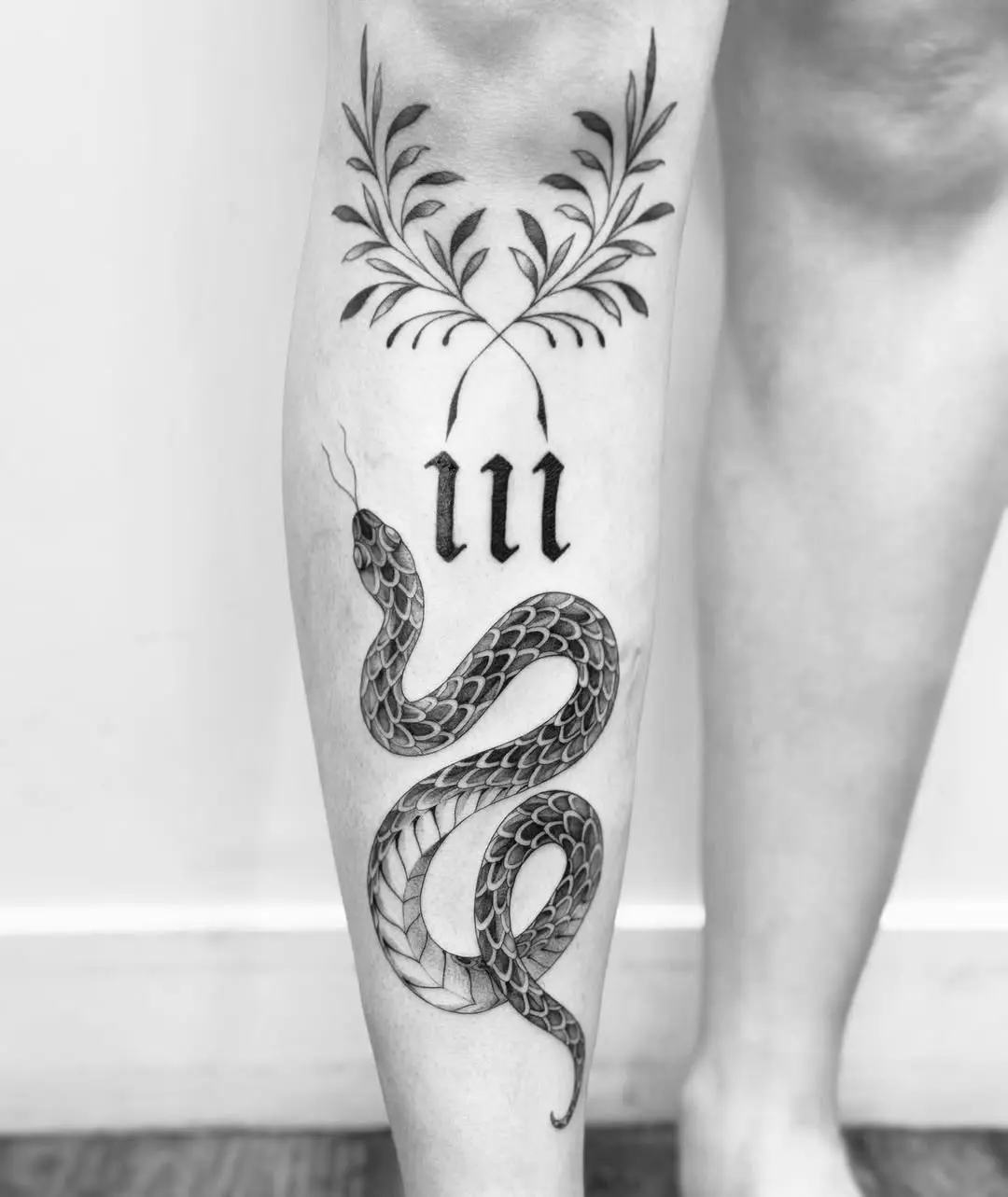Intricate snake and floral shin tattoo design