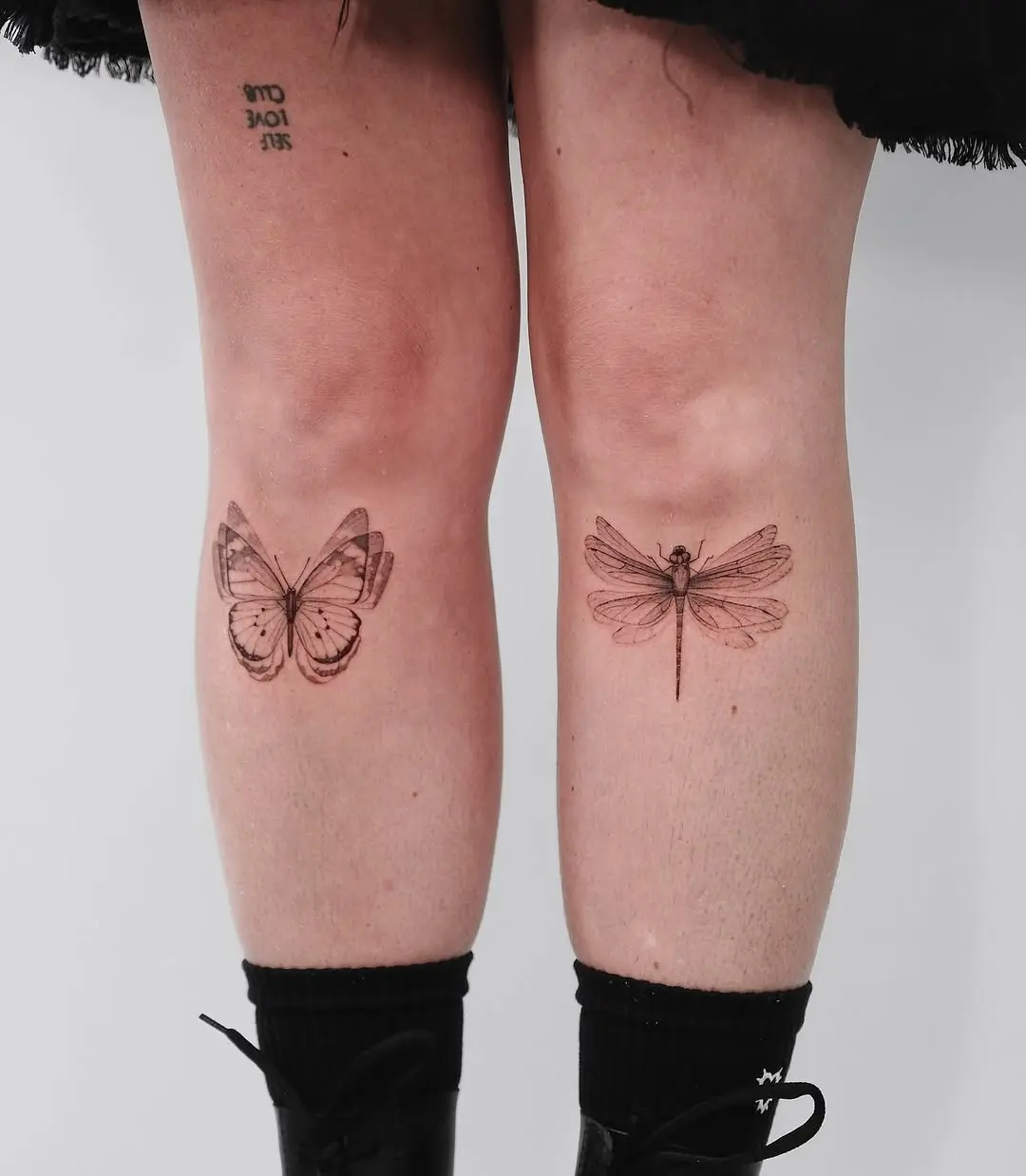 Elegant insect tattoos adorn this person's shins