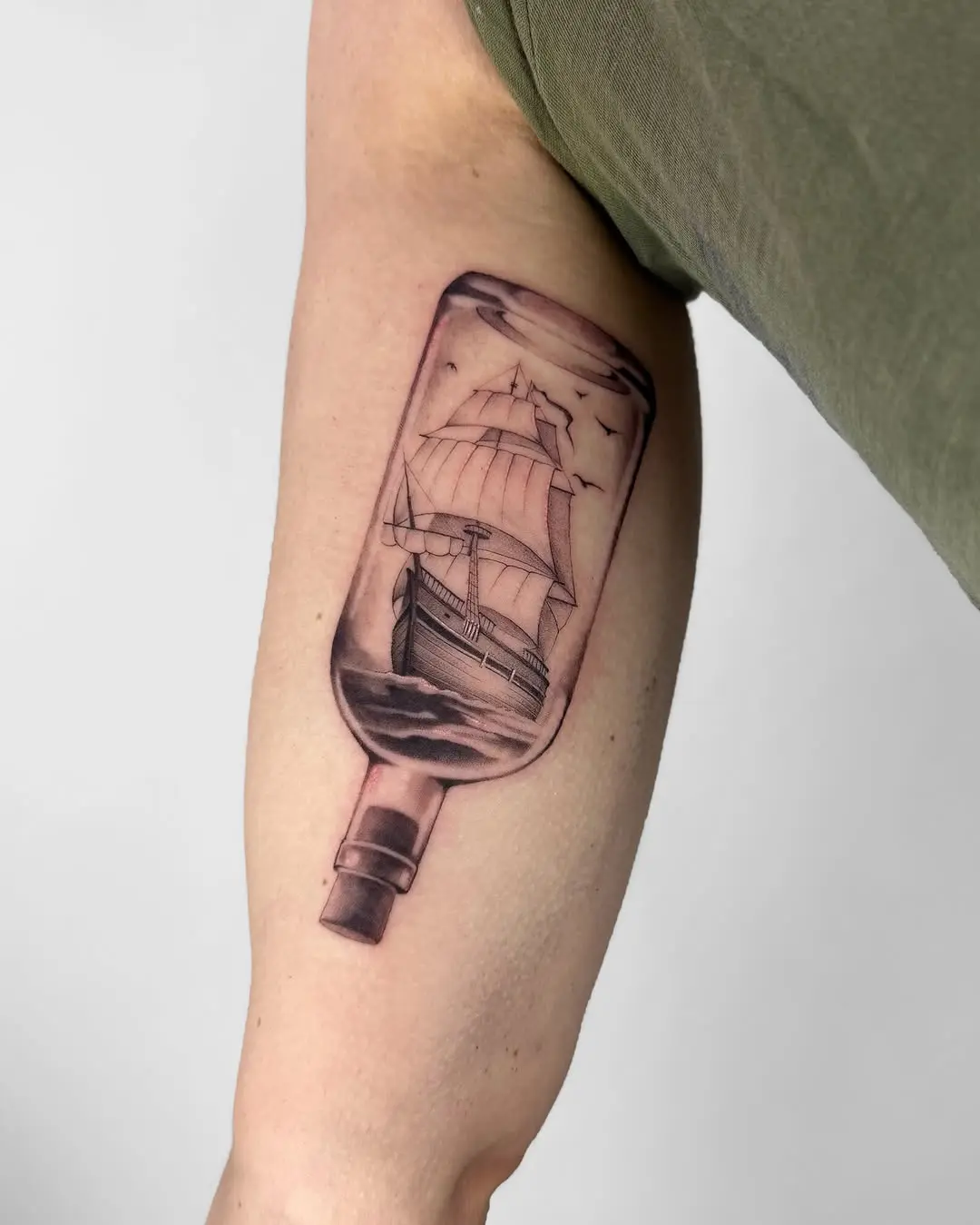Intricate ship tattoo inside a bottle