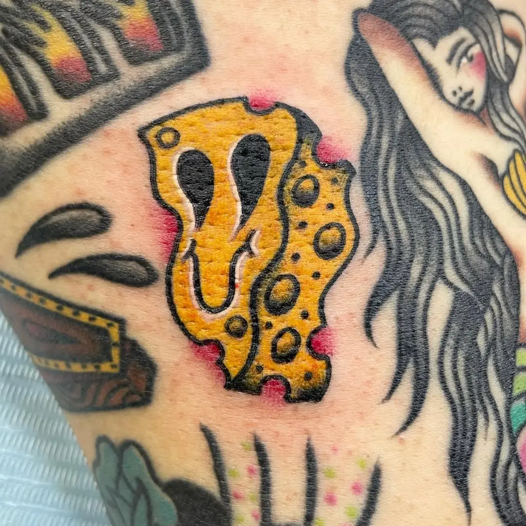 Whimsical smiling cheese tattoo on skin