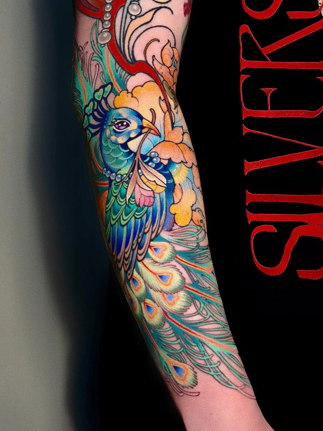 Stunningly vibrant peacock tattoo on forearm