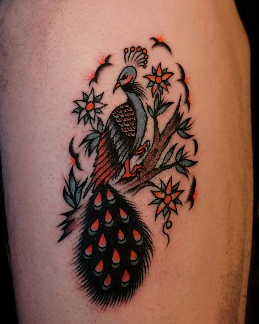 Colorful peacock tattoo surrounded by floral elements