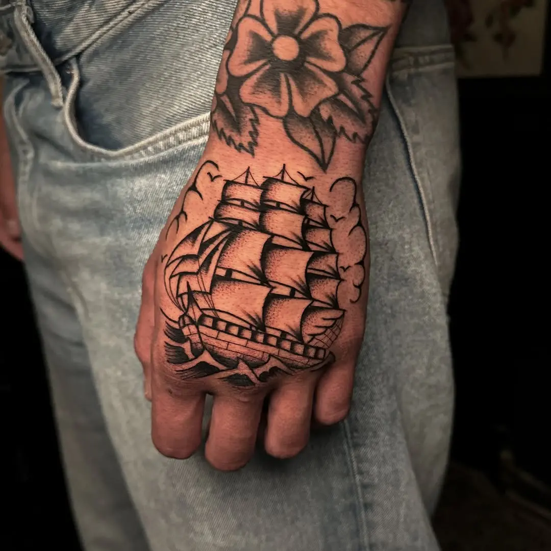 Intricate ship tattoo on hand with floral design