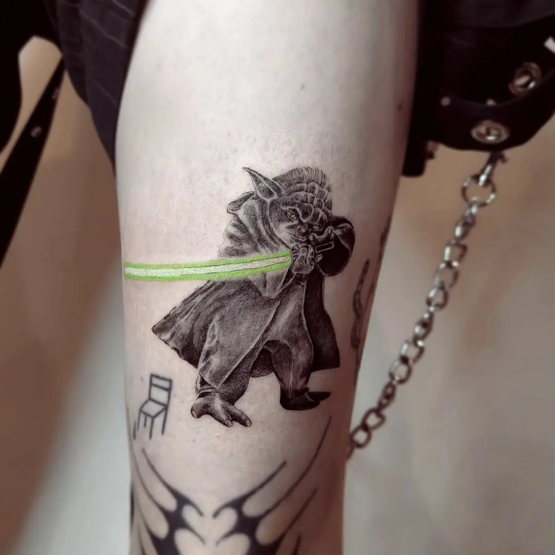 Intricate Yoda tattoo featuring a lightsaber