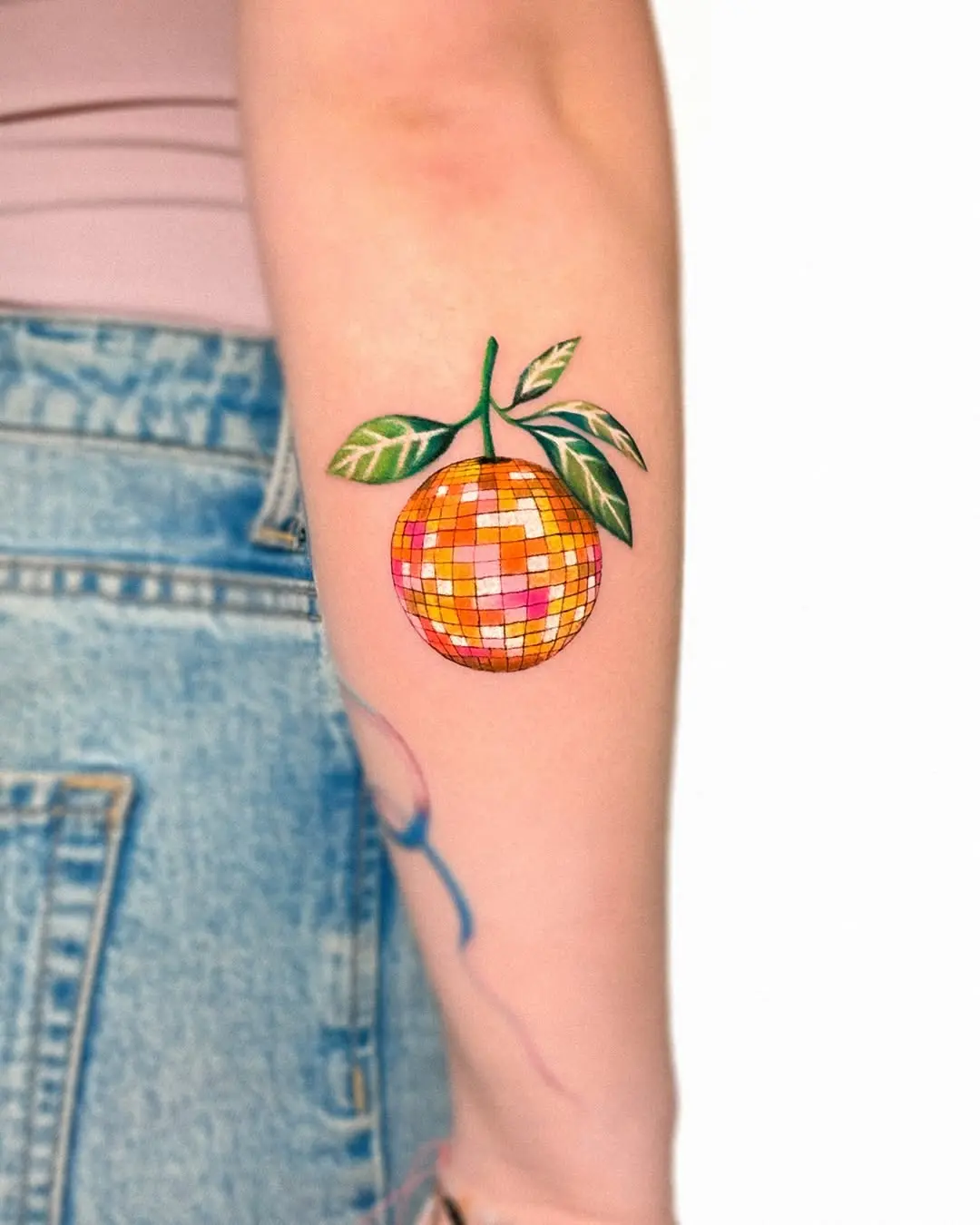 Vibrant orange disco ball tattoo with leaves