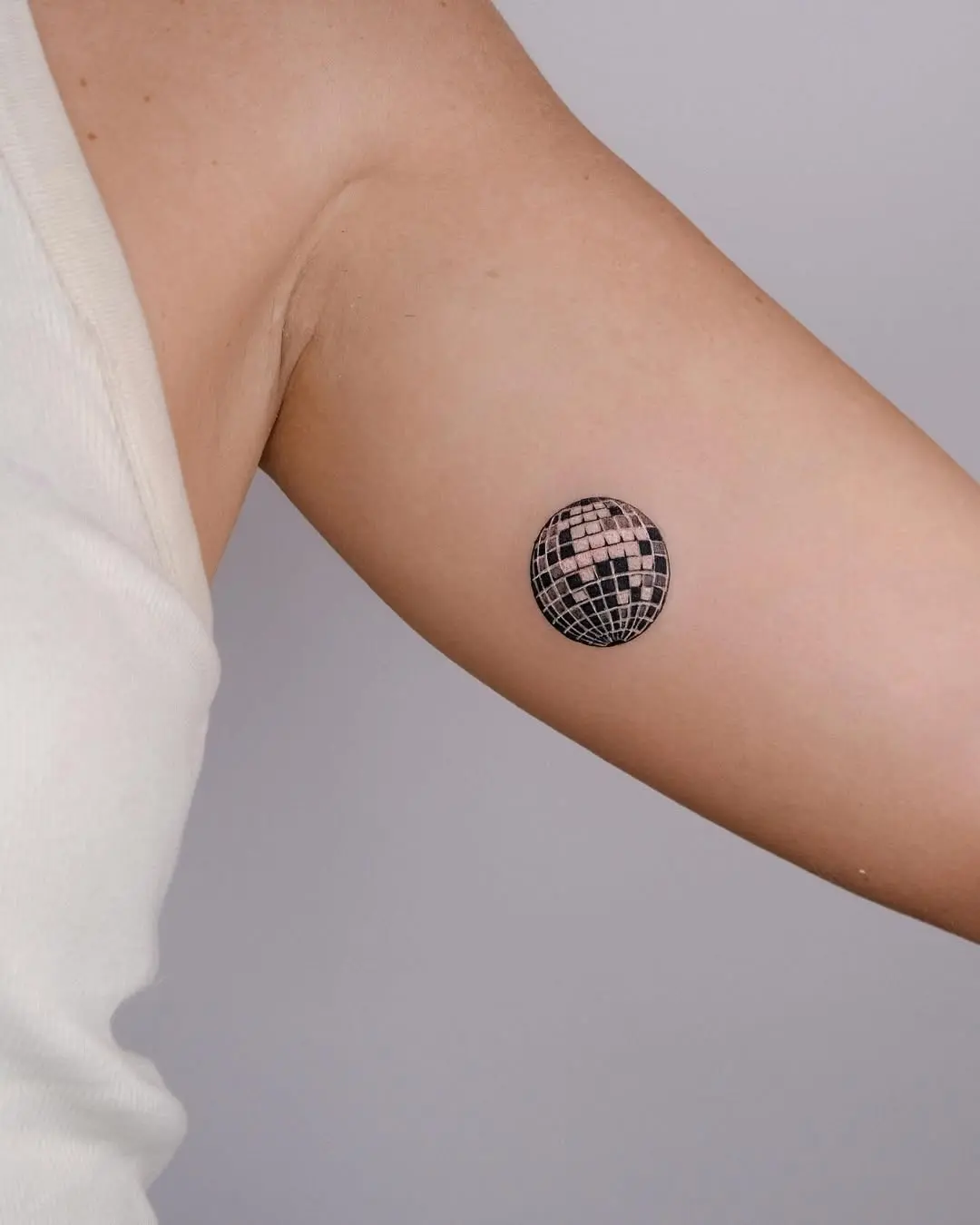Minimalist disco ball tattoo on upper arm