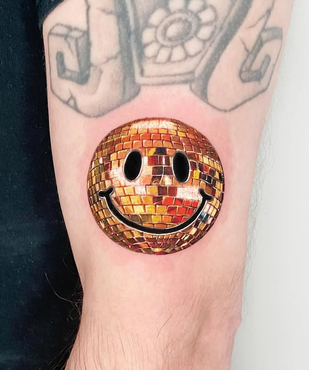 Vivid smiley disco ball tattoo on arm
