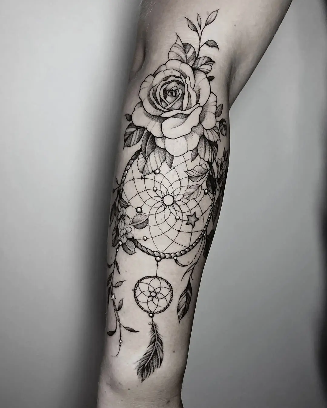 Elegant dreamcatcher tattoo entwined with roses