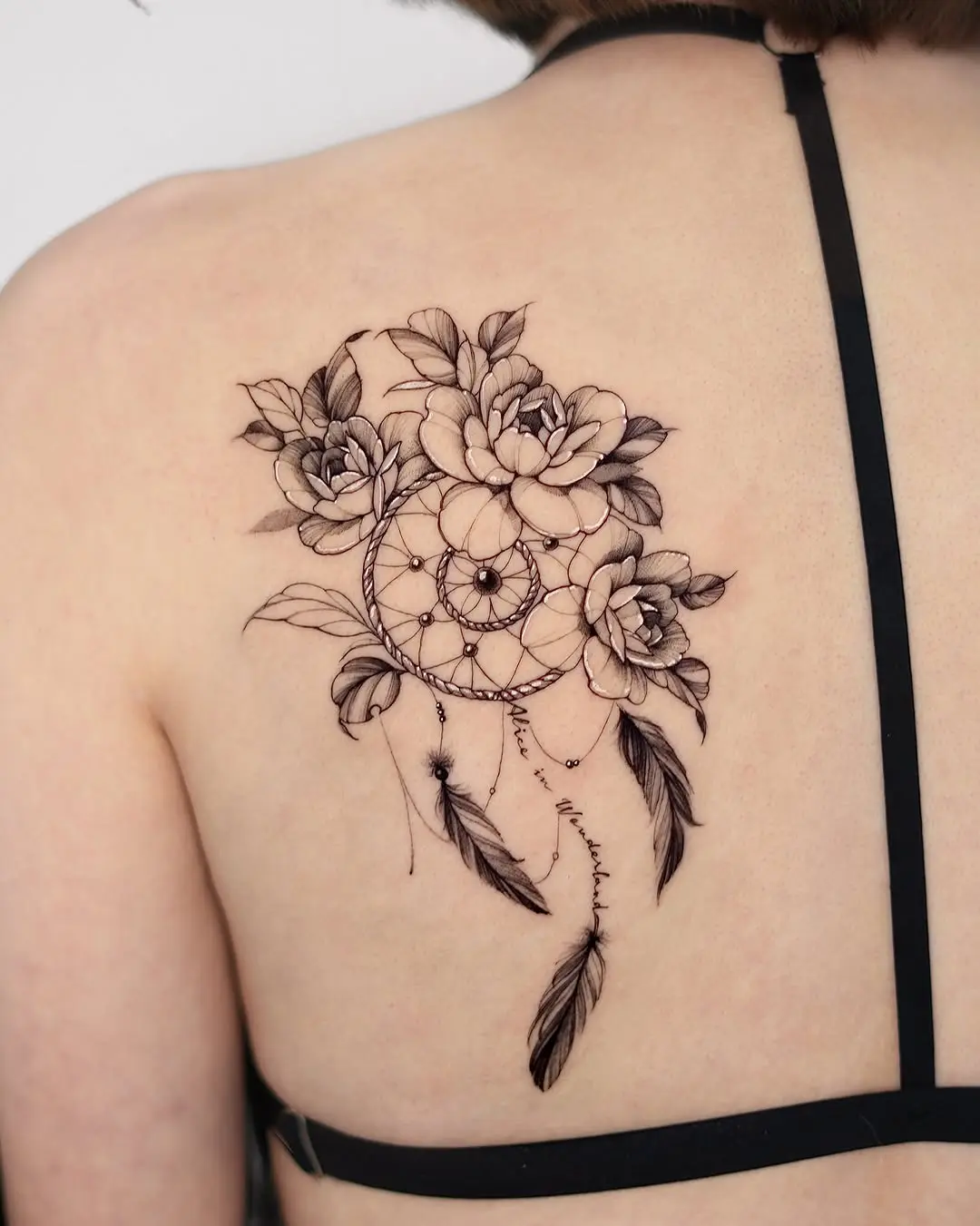 Intricate dreamcatcher tattoo adorned with flowers