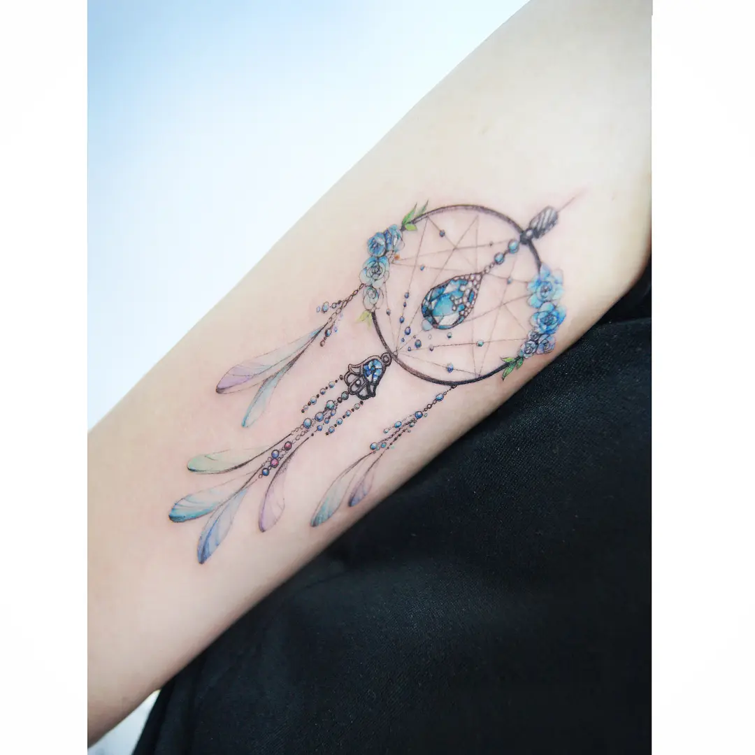 Colorful dreamcatcher tattoo adorned with flowers