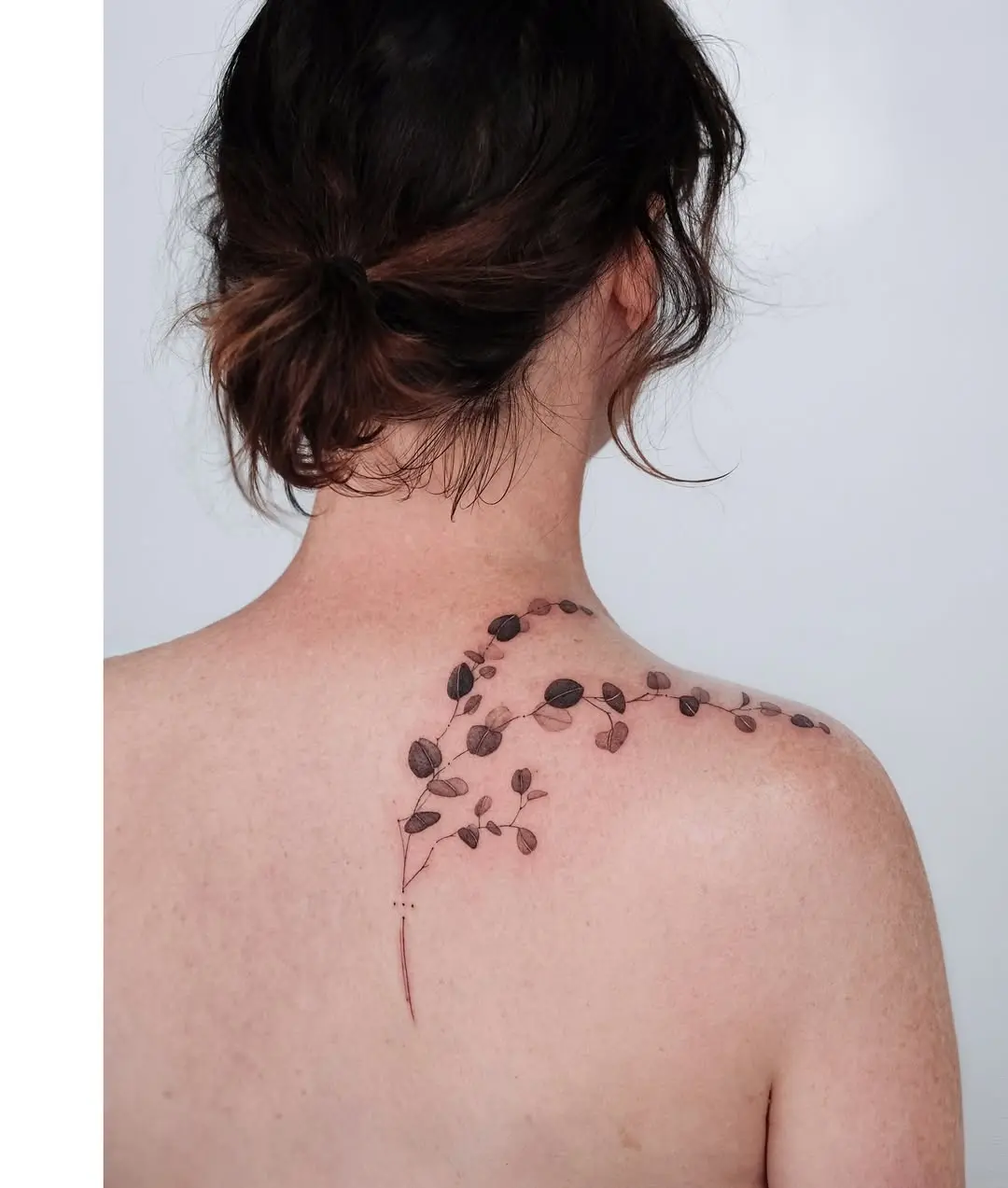 Elegant eucalyptus tattoo on the back shoulder.
