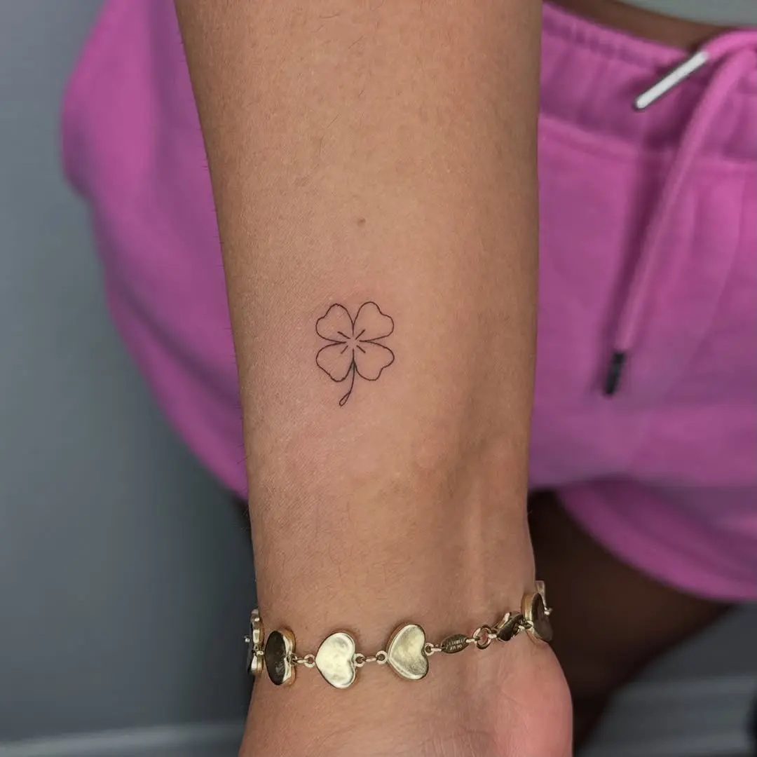 Minimalist four leaf clover tattoo on forearm