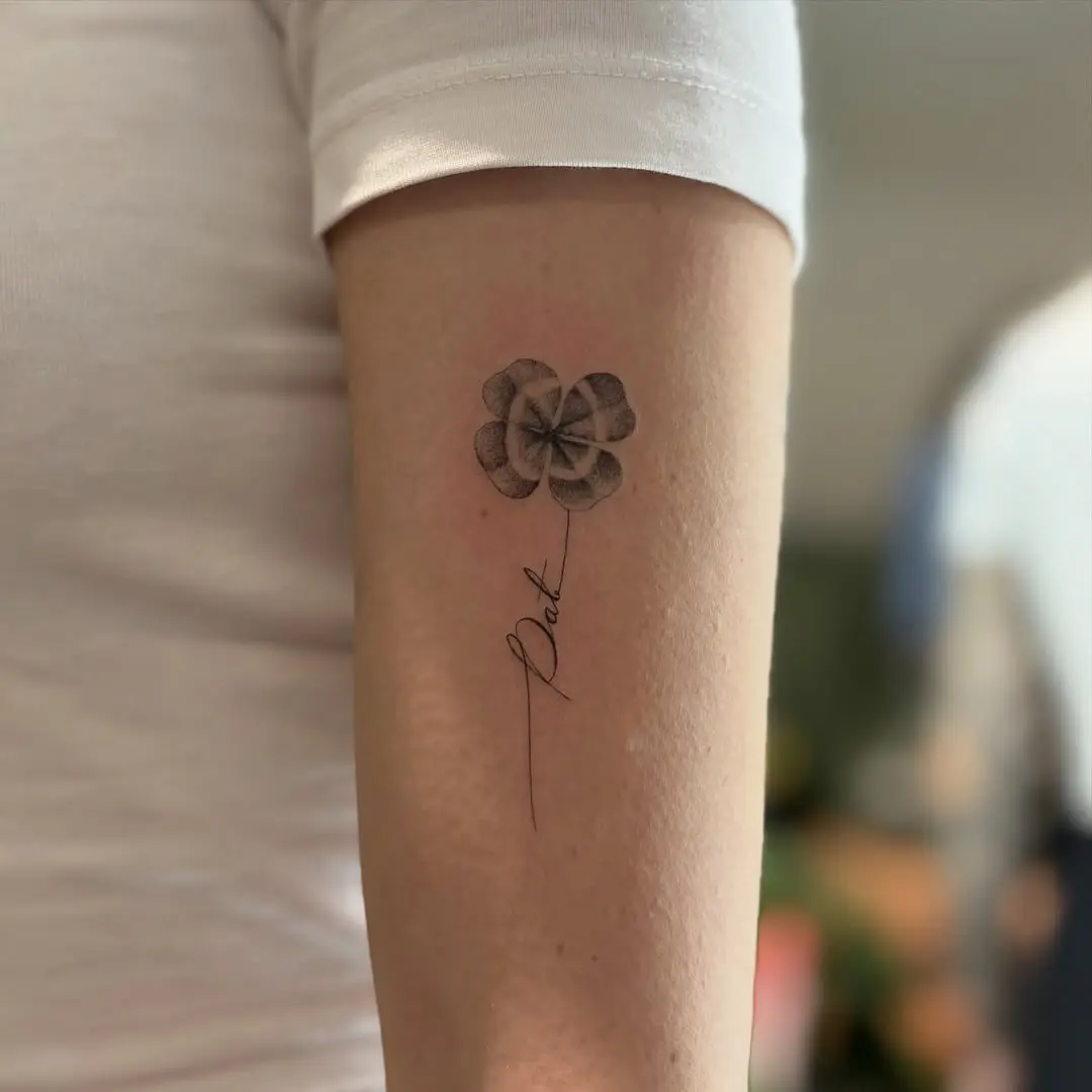 Intricate four leaf clover tattoo with elegant script