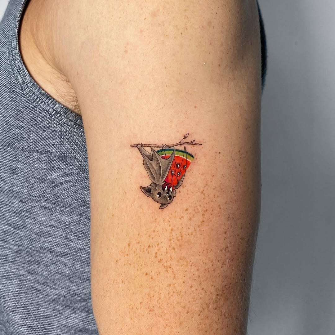 Whimsical bat hanging from a watermelon slice.