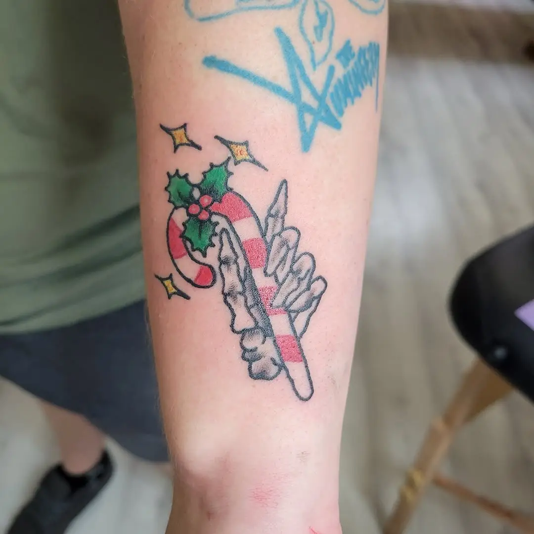 Playful candy cane tattoo with festive holly accents