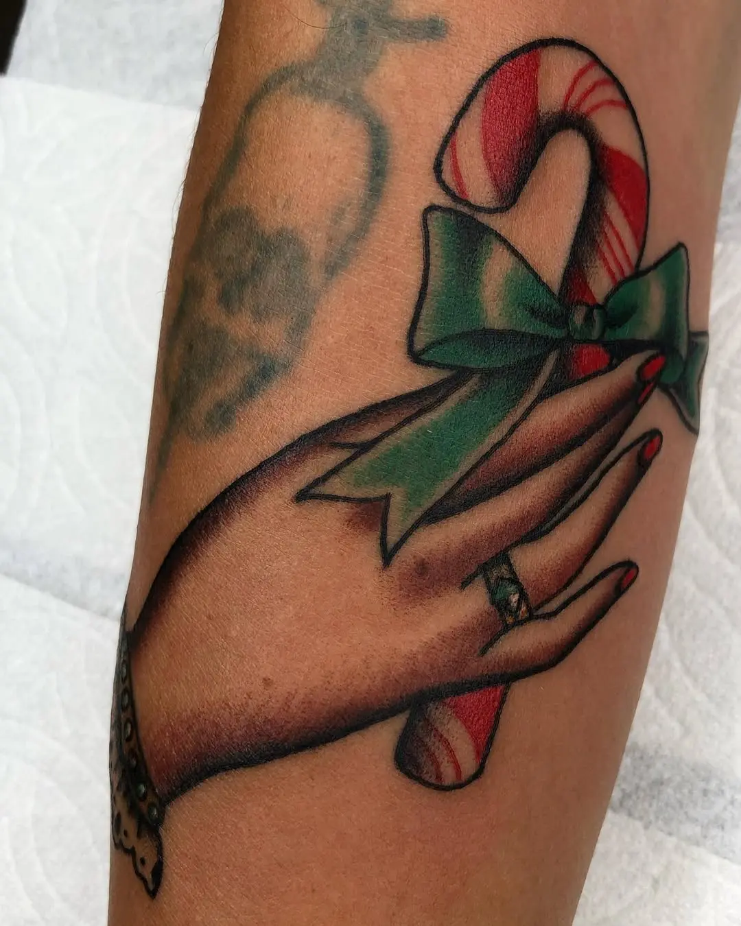 Whimsical candy cane tattoo wrapped in a bow