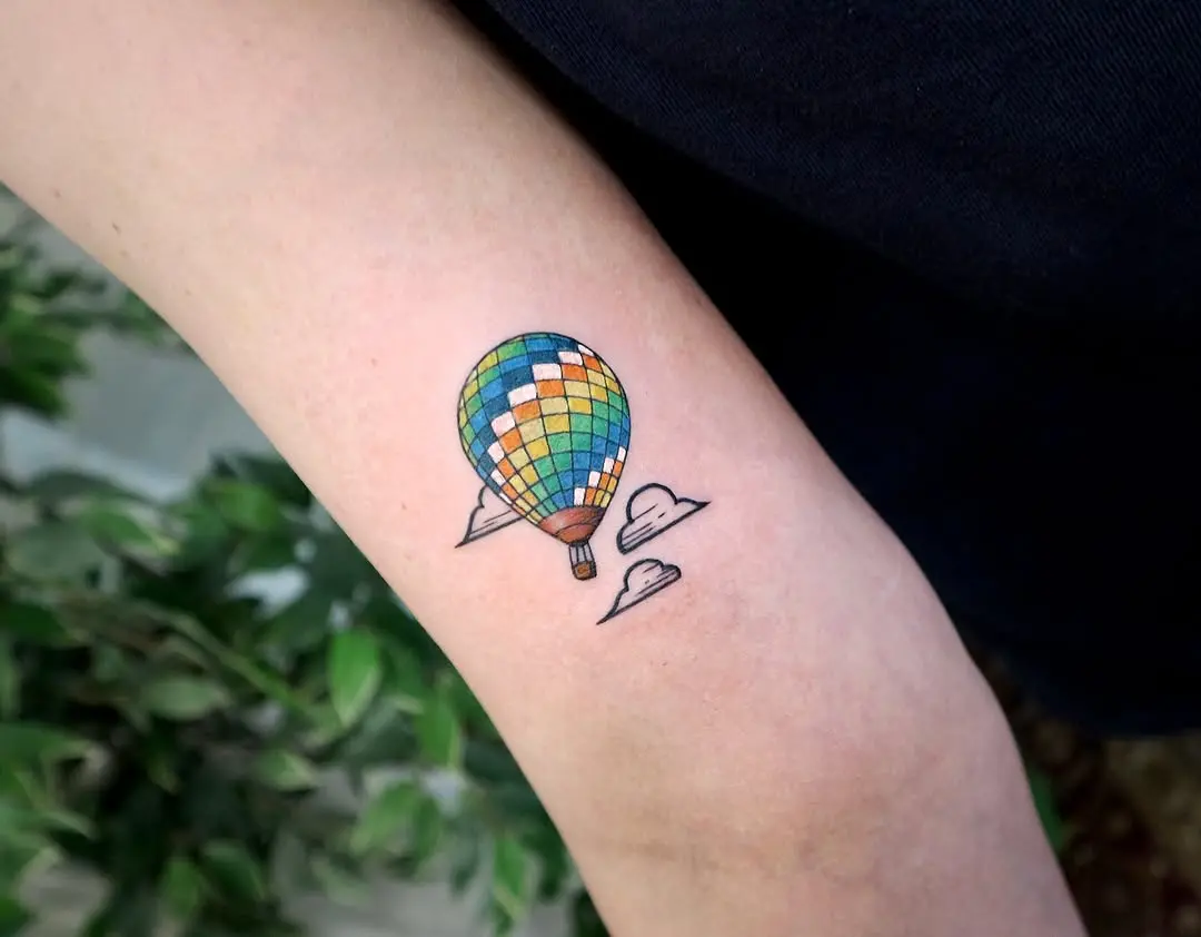 Vibrant hot air balloon tattoo with whimsical clouds