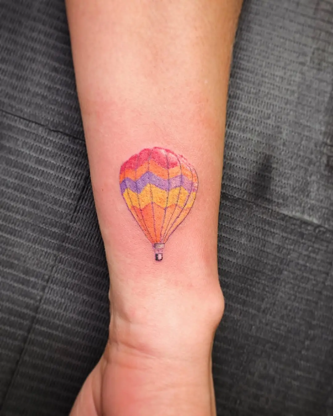 Vibrant hot air balloon tattoo on forearm
