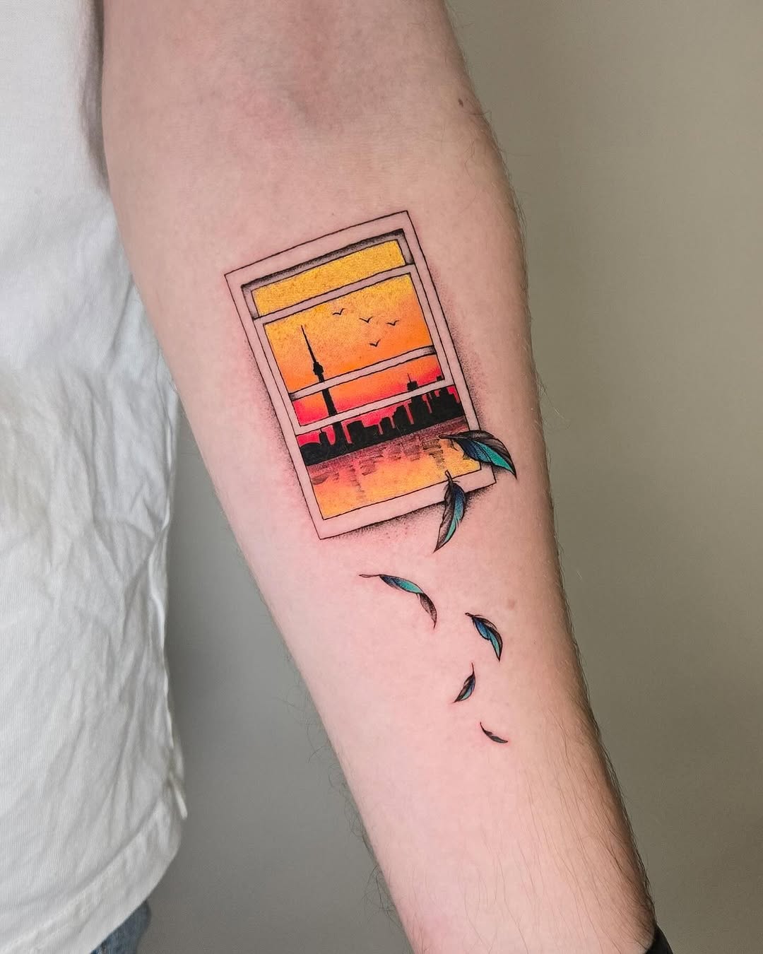 Vibrant skyline tattoo featuring sunset and birds