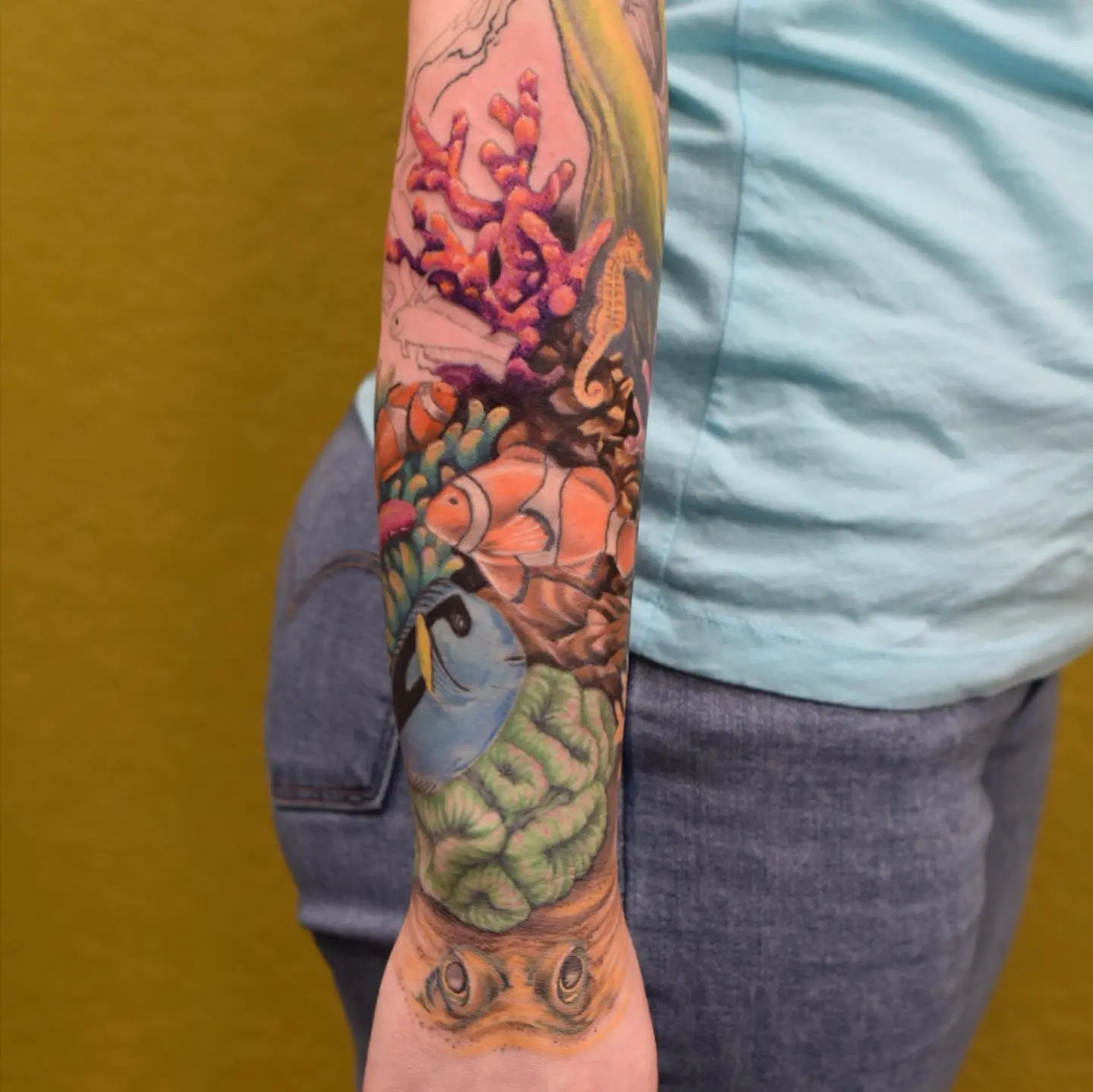 Colorful coral reef tattoo wraps around forearm