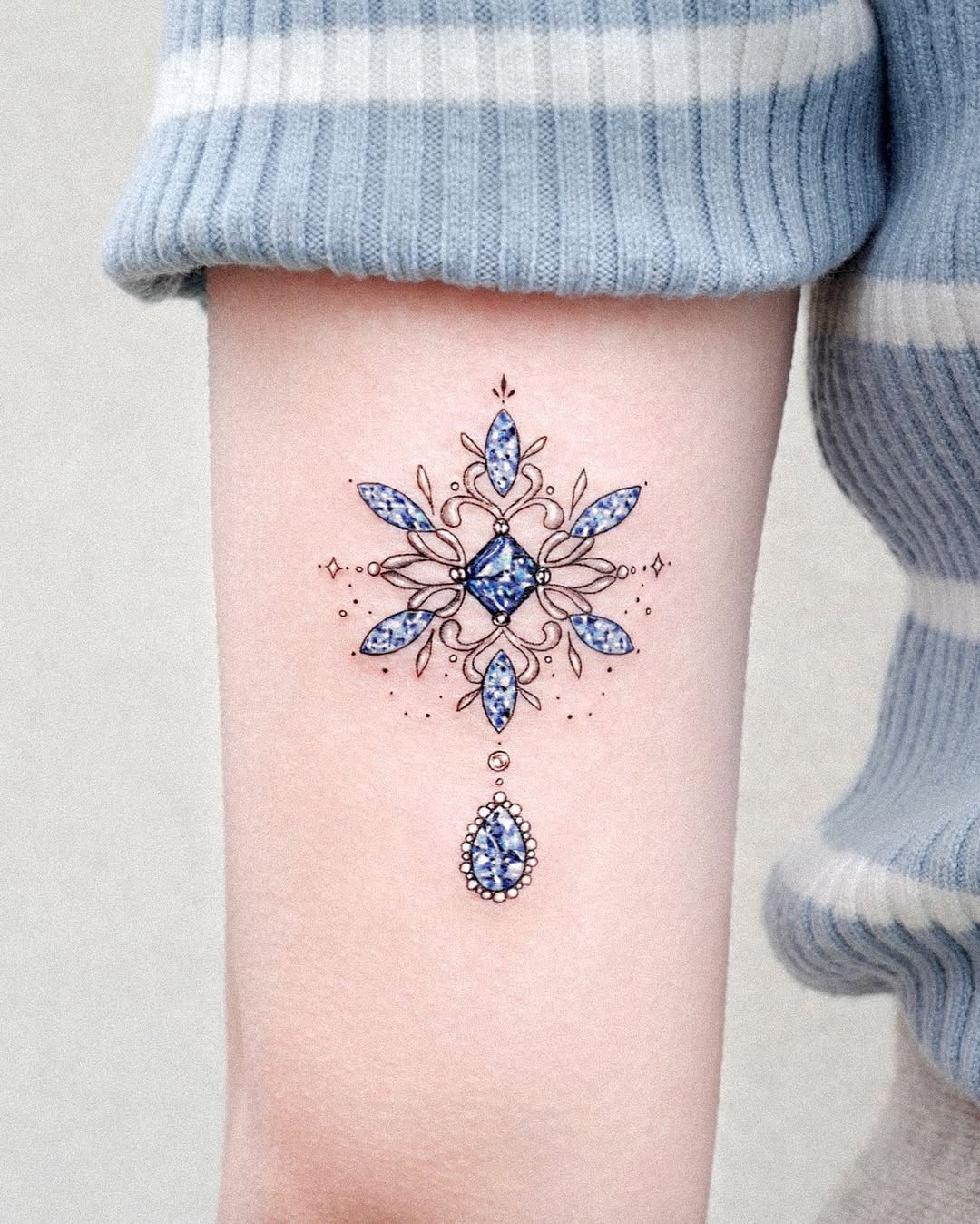 Intricate blue snowflake tattoo with gem-like accents